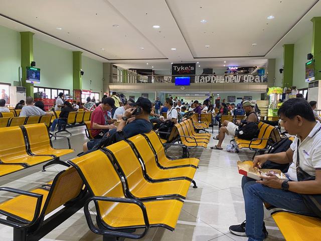 Multiple rows of yellow chairs in a waiting room for the ferry.