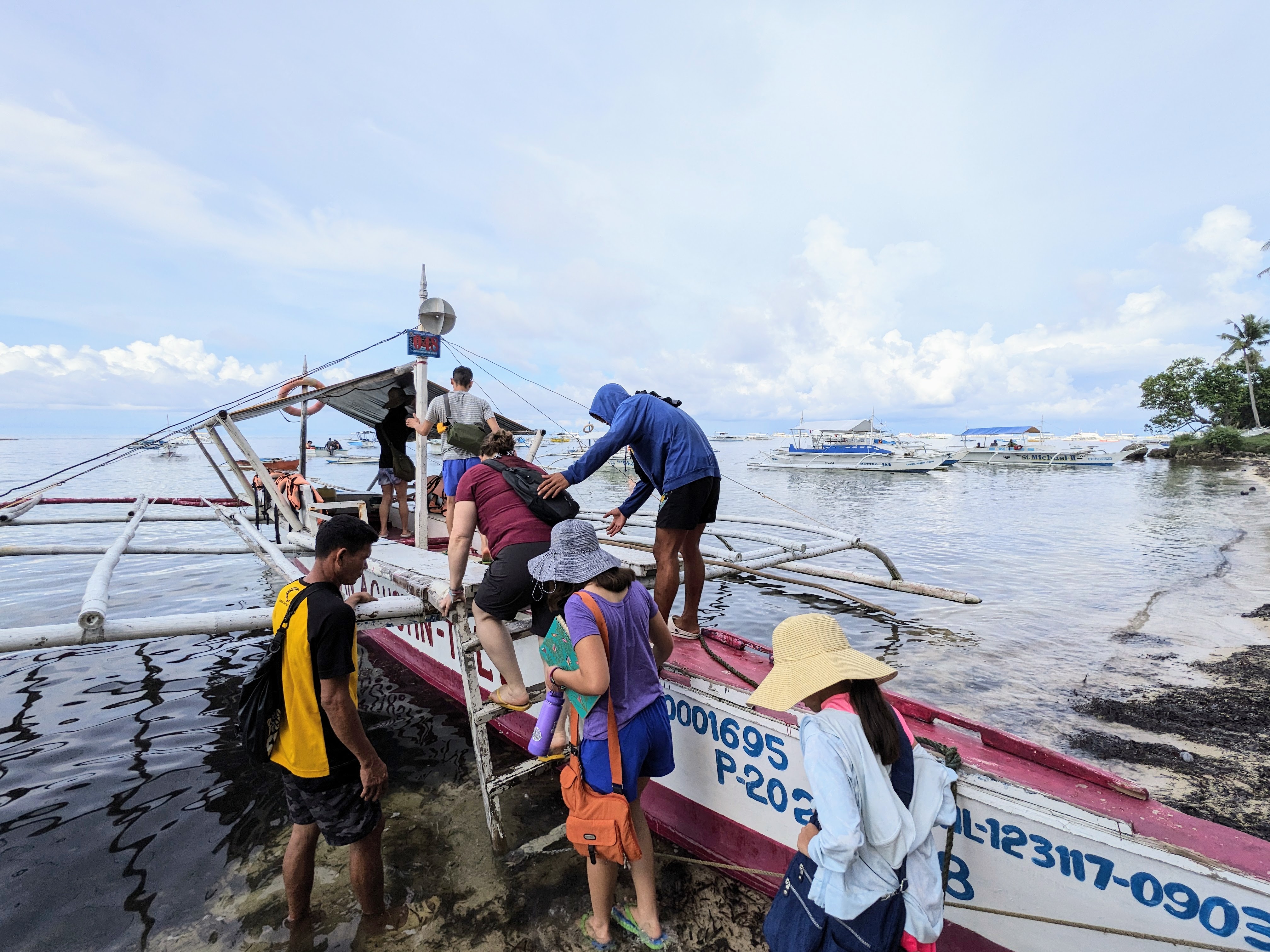Photo © Joseph Llobrera A family boards an outrigger boat using a short set of wooden stairs.