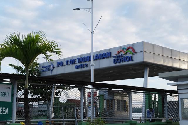 A sign above an entry gate to a port, with a missing letter so it reads “Pot of Tagbilaran”.