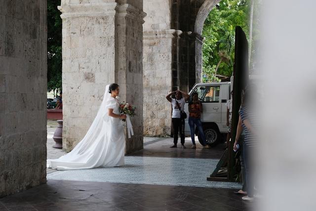 A bride holding a bouquet waits to enter a church for her wedding.
