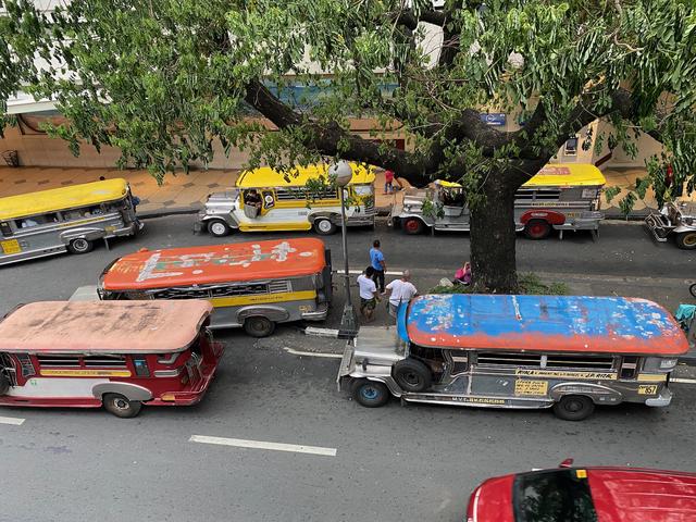 Colorful jeepneys queued up for passengers, viewed from an elevated walkway above.
