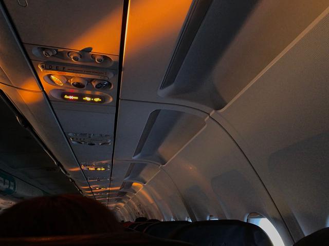 Sunset streaming into the inside of an airplane cabin, lighting up the overhead air conditioning nozzles.