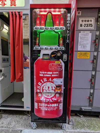 A vending machine for sriracha hot sauce, shaped like a bottle of sriracha.