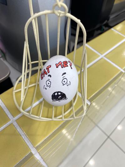 An egg decorated with a face and the words “Eat Me?”.
