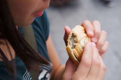 Closeup of a girl biting into an ice cream sandwich.