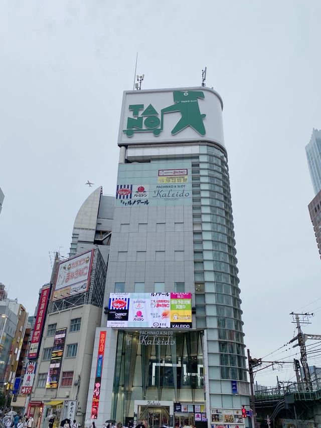 A tall building topped with an advertisement for Tano, featuring a cartoon dog with Tano-kun written across its neck like a collar.