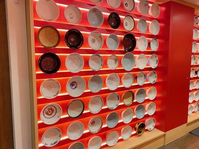 Rows of different ramen bowls mounted on a wall.