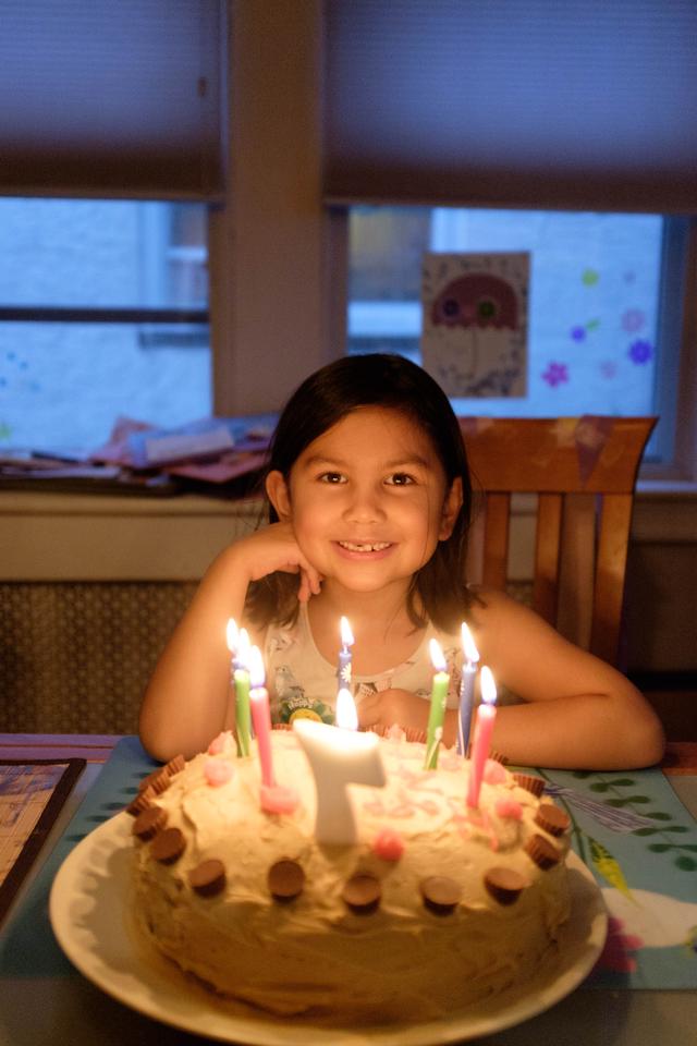 Girl with a birthday cake lit by candles.