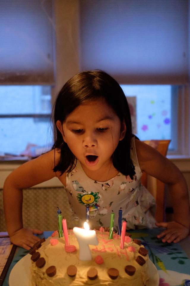 Girl blowing out a “7” candle on a birthday cake.