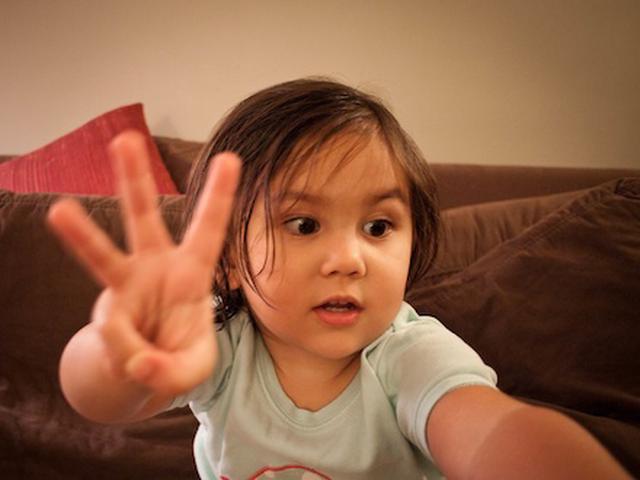 A girl holds up three fingers
