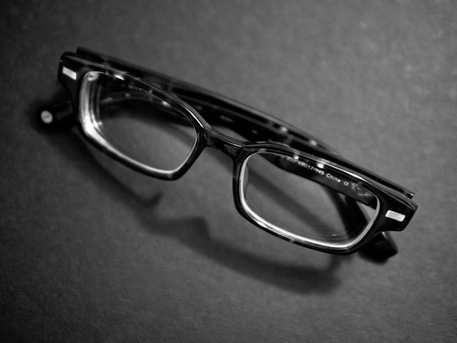 Black and white shot of eyeglasses folded, on a table.