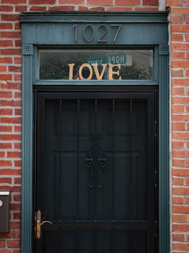 Door with a sign saying "Love", with a reflection of a street sign saying "Hope".